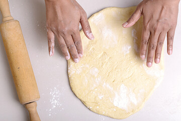Hands making dough with a rolling pin