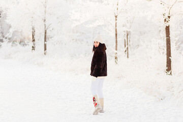 smiling young woman goes in boots and fur coat in winter. ideas for winter photo shoot