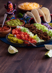 Vertical view of taco shells with a platter of all the fixings ready for eating.