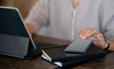 Cropped image of woman hands using smartphone and tablet computer while sitting in modern office.