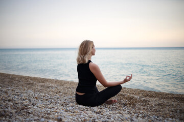 Fototapeta na wymiar young beautiful woman meditates by the sea