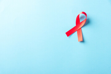 Red bow ribbon symbol HIV, AIDS cancer awareness with shadows, studio shot isolated on blue background, Healthcare medicine concept, World AIDS Day