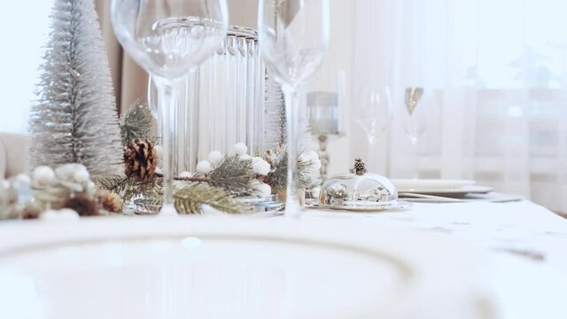 A girl in a white dress serves carnival at the Christmas table. Festive table setting