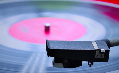 The pickup head of a turntable against the background of a vinyl record