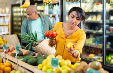 Man and woman picking ripe tomatoes together at grocery store