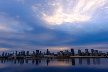 Obraz premium 大阪淀川河川敷から見た梅田。早朝厚い雲からわずかに朝日が顔を出す