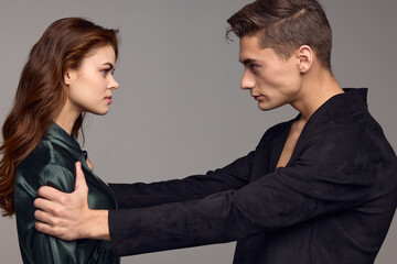 Sexy man in a jacket and a woman on a gray background opposite each other