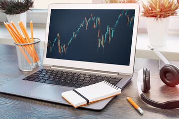 Stock exchange trade and forex financial concept. Laptop with graphs headset on wooden desk near...