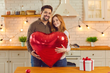 Happy couple holding huge balloon while celebrating Valentine's Day or having anniversary party