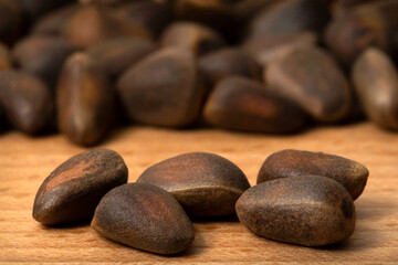 Five pine nuts and a bunch of nuts on a wooden background.