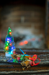 Christmas tree with lights on the background of a fireplace with wood. cozy house, waiting for Christmas.