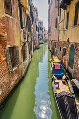 Small canal with traditional gondola seen in Venice, Italy