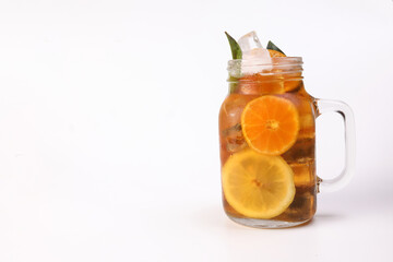 Liquid ice lemon orange tea with slice green leaf cinnamon stick in transparent glass jar mug on white background