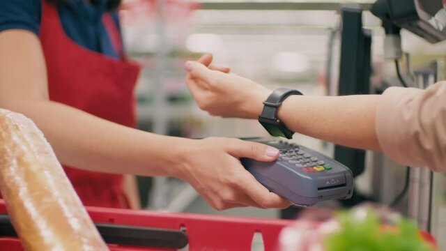 Midsection footage of unrecognizable woman using non-contact payment paying with smart watch holding it near payment terminal