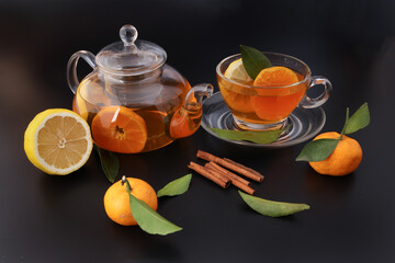 Liquid tea lemon orange slice green leaf cinnamon stick in transparent glass teacup saucer teapot...