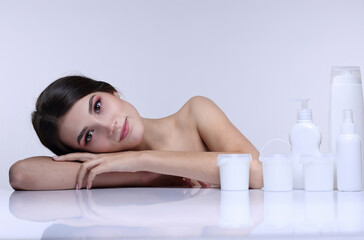 Obraz na płótnie Canvas Beauty portrait of a girl with shampoo, soap and creams on a light background