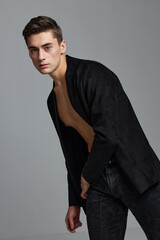 A young man in a classic suit leaned to the side against a gray background