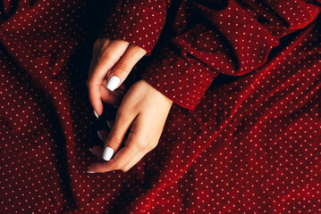 White female manicure on polka dot fabric background.