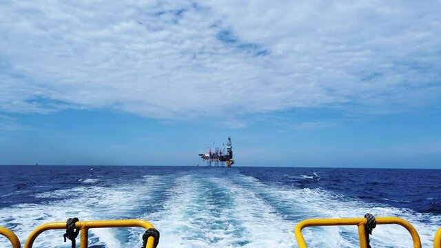 Crew boat sailing to the offshore jack up drilling rig in the middle of the ocean
