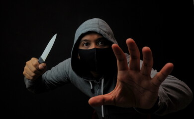 man in mask holding knife in the dark, violence crime or robbery illustration
