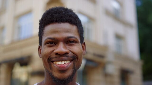 Cheerful african man posing in city. Guy looking at camera with smile outdoors