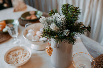 Christmas decorations. Fir branches with snow inside the vase on the christmas table. Decoration of...