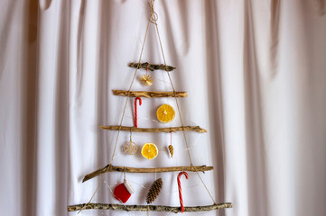 Hand made eco friendly christmas tree out of wooden sticks, oranges, cones and lights.  Сhristmas tree in scandinavian style.