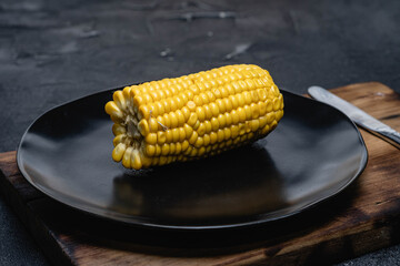 primer plano macro de choclo hervido con manteca y sal menu de niño sobre plato negro y fondo oscuro cordoba argentina