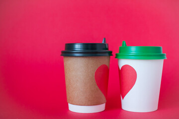 disposable paper cups with red heart on bright red background. Valentine's Day.
