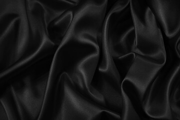 Black silk satin fabric background. Black elegant background. Dark liquid wave or black silk with wavy folds.