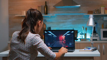 Young woman gamer playing online professional game on laptop at home late at night. Professional player testing online video games on her personal computer with modern technology network wireless. © DC Studio