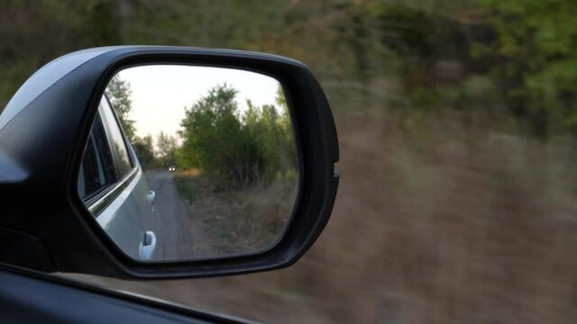 4K video of driving car on forest road, closeup front mirror view reflaction