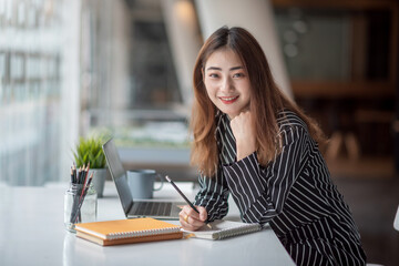 Obraz na płótnie Canvas Portrait of young asian businesswoman beautiful charming smiling sitting working at office. Look at camera.