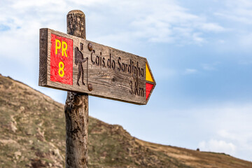 Hiking path sign PR 8 in front of rocky cliffs at Ponta de Sao Lourenco, the island of Madeira,...