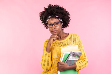 Beautiful young african american woman holding notebooks, wearing glasses. Having thinking face. Student life
