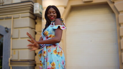 Excited afro girl dancing latino dance in city. Girl turning around on street