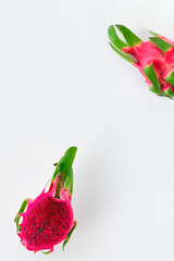 Fototapeta premium Creative flat layout with fresh organic pink dragon fruit, pitaya or pitahaya cut in half. Trendy top view on white background with text space.