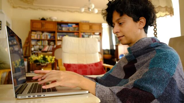 Home office working environment. Using laptop and working efficiently. Using technology and working at home productively. Young female adult study focused.