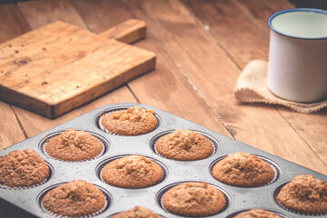 Group of muffins inside the baking tin on a wooden table