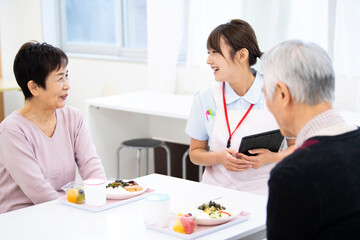 食事をしながら楽しそうに会話をする施設の入居者と女性職員