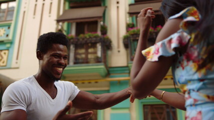 Cheerful afro dancers moving in slow motion in city. Couple dancing on street - obrazy, fototapety, plakaty