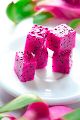 Pink dragon fruit, pitaya or pitahaya cut in cubes on white plate. Trendy superfood ingredient. Close-up on the slices, fruit cubes in white plate.