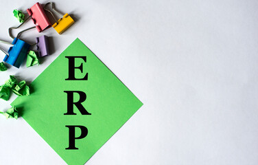 ERP - word on green note paper with stationery clips and buttons on a white background