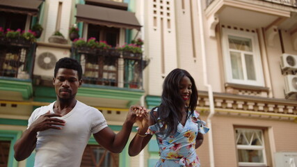 Afro couple dancing on street. African dancers making movements outdoors.