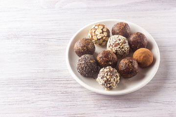 Raw vegan healthy energy balls with oatmeal, cereals, chia seed, coconut flakes, cocoa and dried fruits. Copy space.