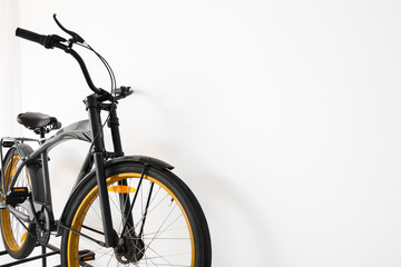 Modern bicycle near light wall