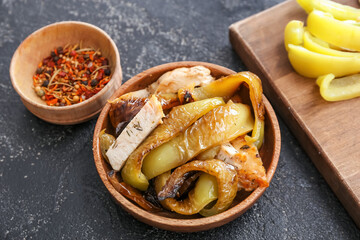 Wooden bowl with roasted bell pepper and spices on dark background