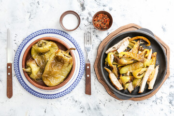 Plate and bowl with roasted bell pepper and meat on light background