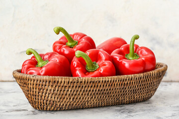 Red bell pepper in wicker bowl on light background