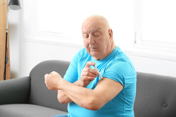 Senior diabetic man giving himself insulin injection at home